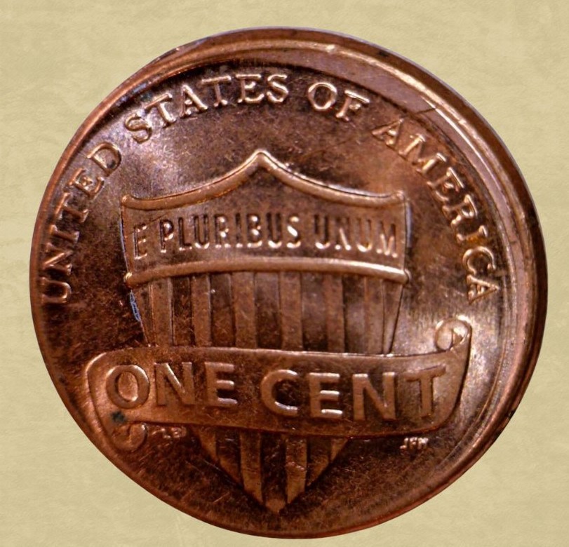 2010 penny off-center strike error showing Lincoln design shifted with crescent of blank metal at coin edge, date visible